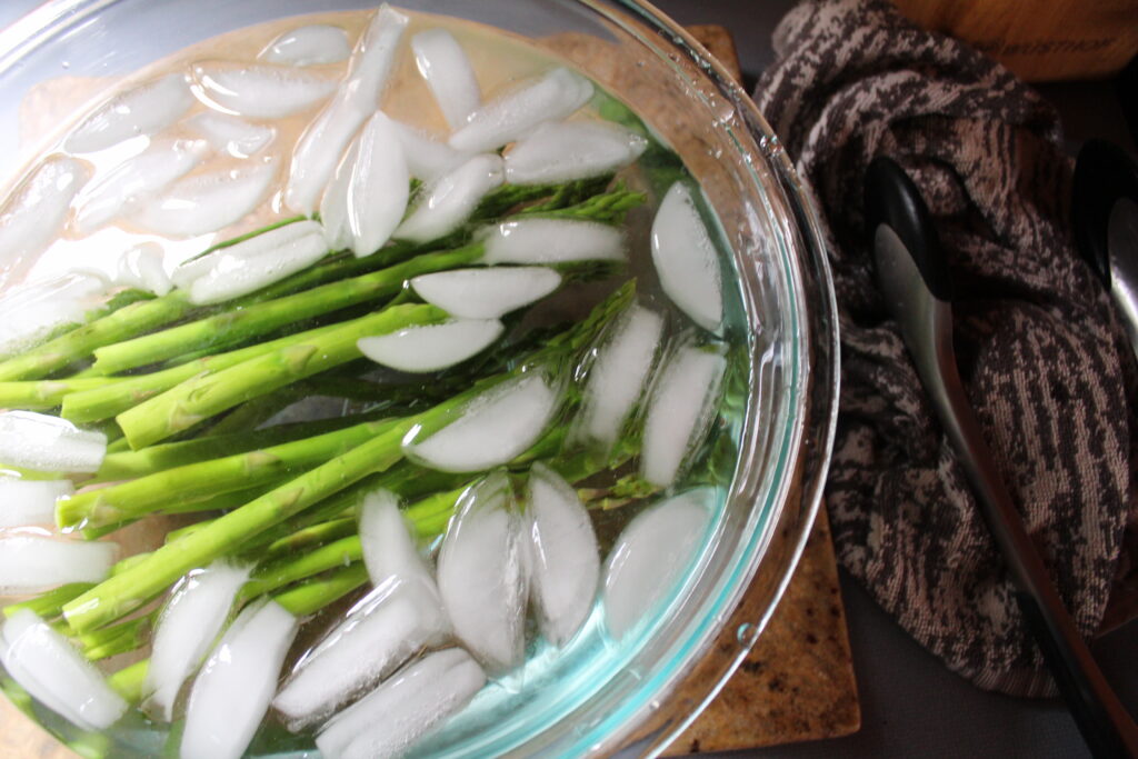 Blanched asparagus rest in an ice bath to stop the cooking process.