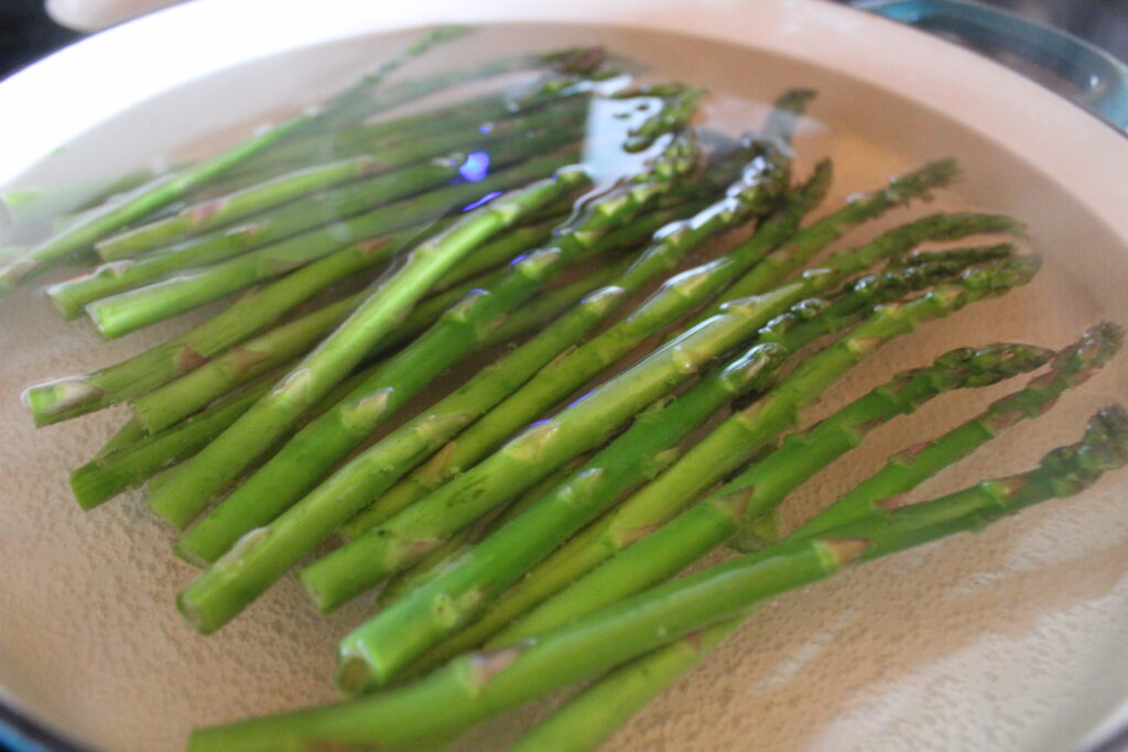 Asparagus is blanched in boiling water in preparation for being frozen