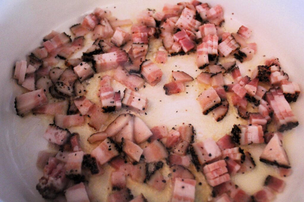 Bacon rendering in an enameled cast iron dutch oven. The ingredient is needed for the best ham, potato and corn chowder.