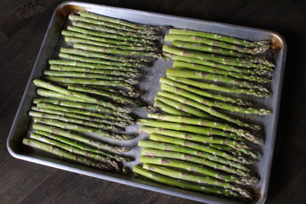 Seasoned asparagus is cut and ready to go in the oven to make Quick and Delicious Roasted Asparagus